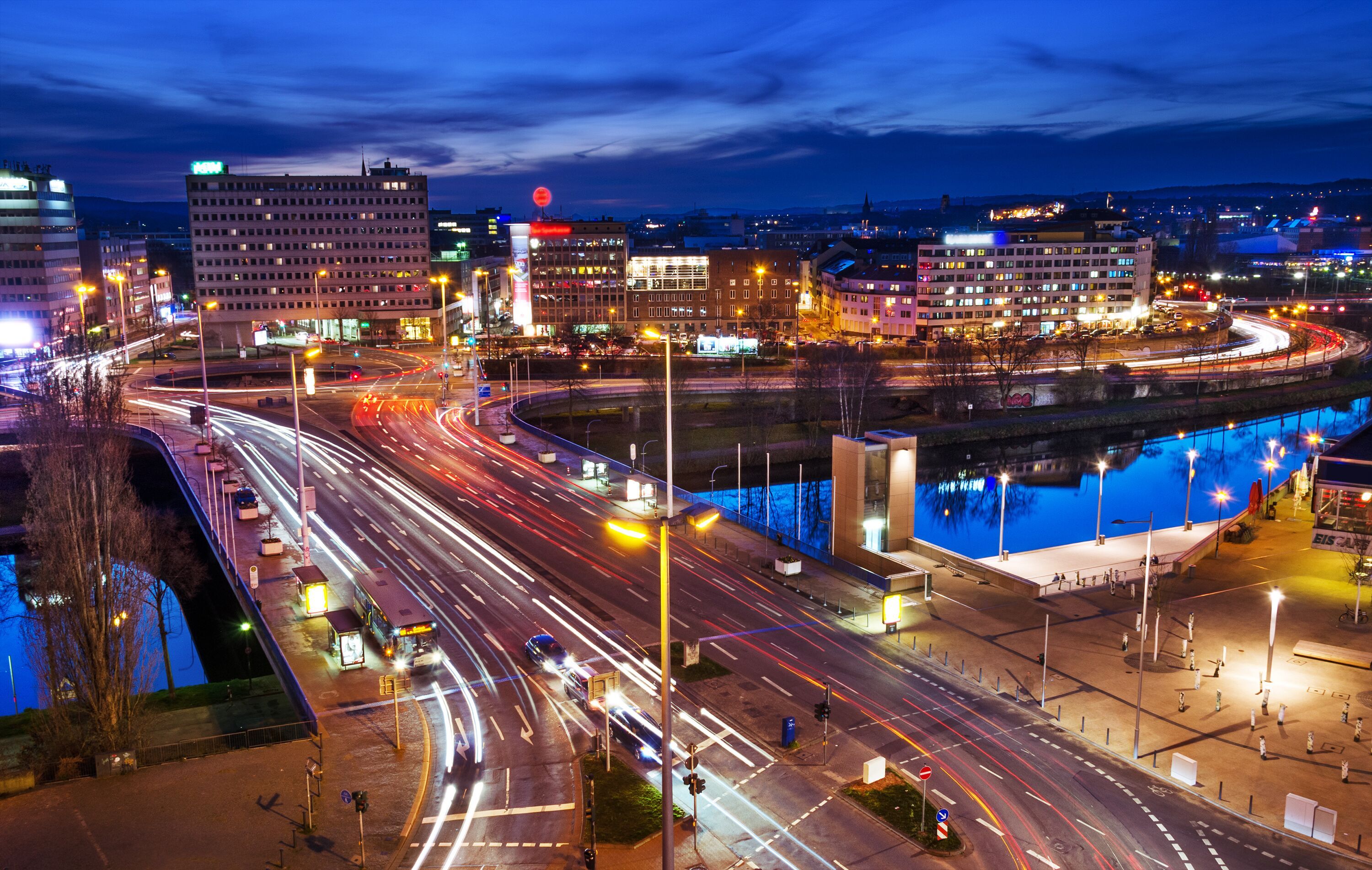 verschwommene Autolichter auf einer Brücke über einem Fluss in der Abenddämmerung